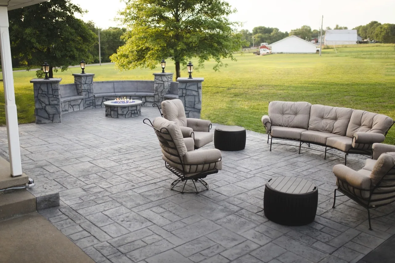 A stamped concrete patio with a fire pit and outdoor seating at a home