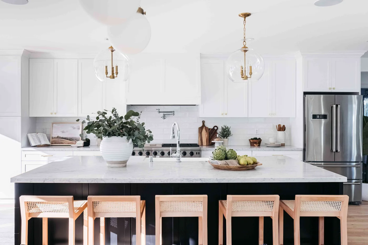Remodeled white kitchen with a large island, pendant lights, and stainless appliances